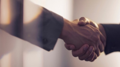 Two people shaking hands in agreement. // Deux personnes se serrant la main en accord.