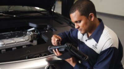 An Acura certified technician is reviewing the diagnostics of the vehicle on a portable tablet. // Un technicien certifié Acura examine les diagnostics du véhicule sur une tablette portable.
