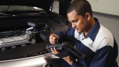 An Acura certified technician is reviewing the diagnostics of the vehicle on a portable tablet. // Un technicien certifié Acura examine les diagnostics du véhicule sur une tablette portable.